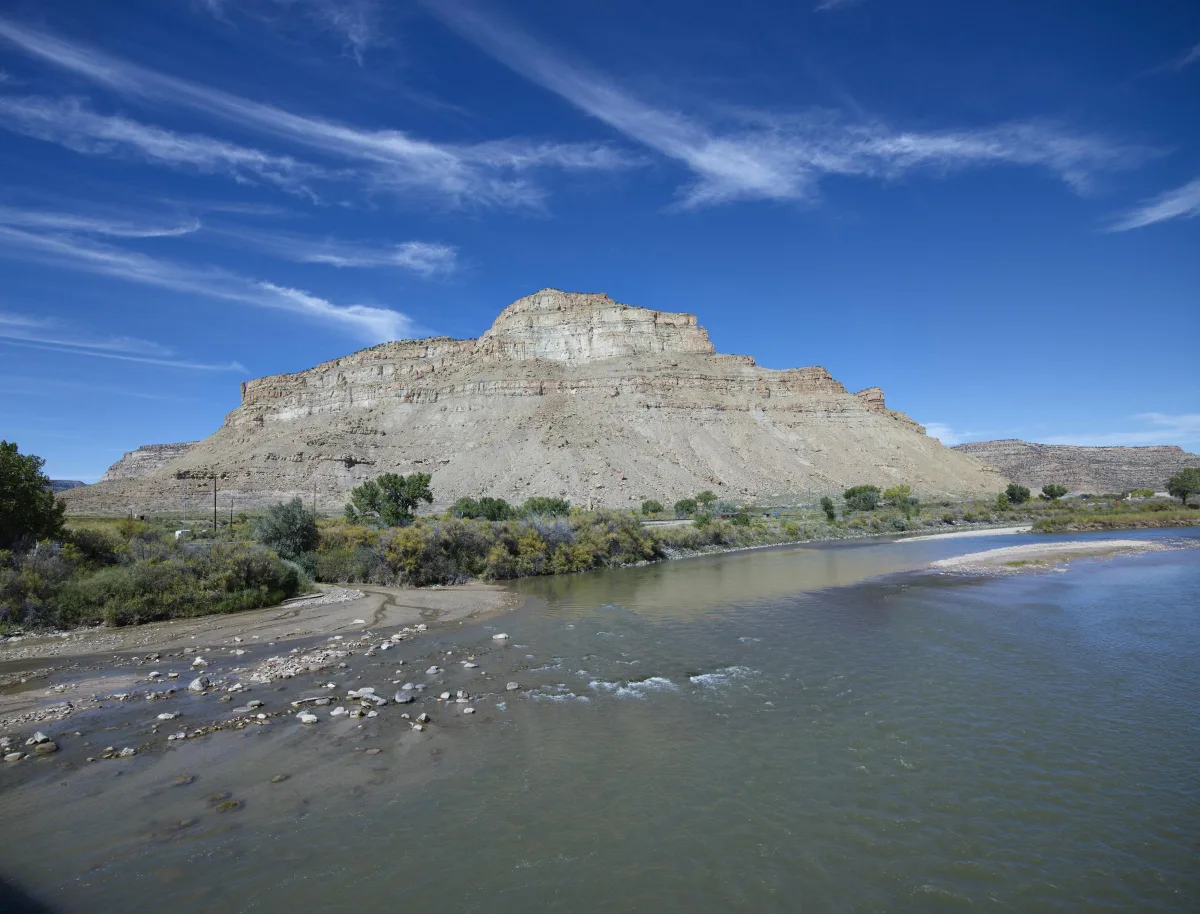A pale bluff rising above the Colorado River near Palisade under a deep blue sky